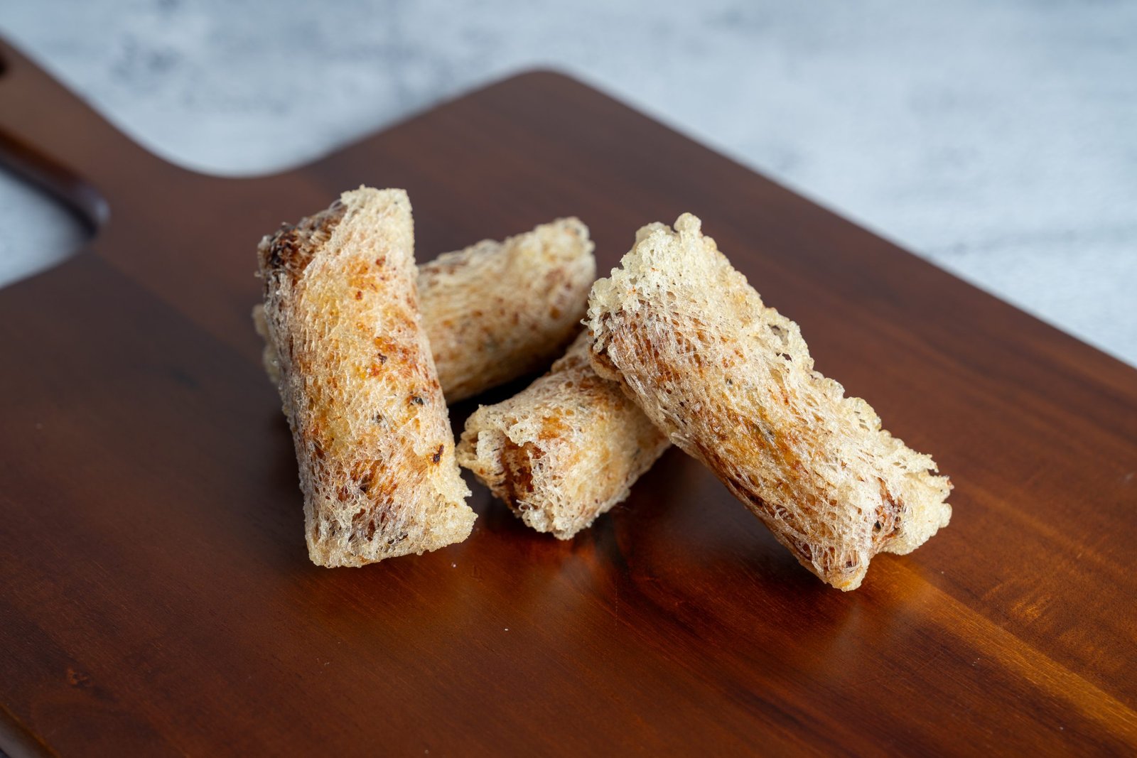 Crispy Vietnamese egg rolls (Chả Gi&ograve;) served on a wooden platter, highlighting the restaurant's traditional cuisine offerings at Carrot & Daikon in Henderson, NV.